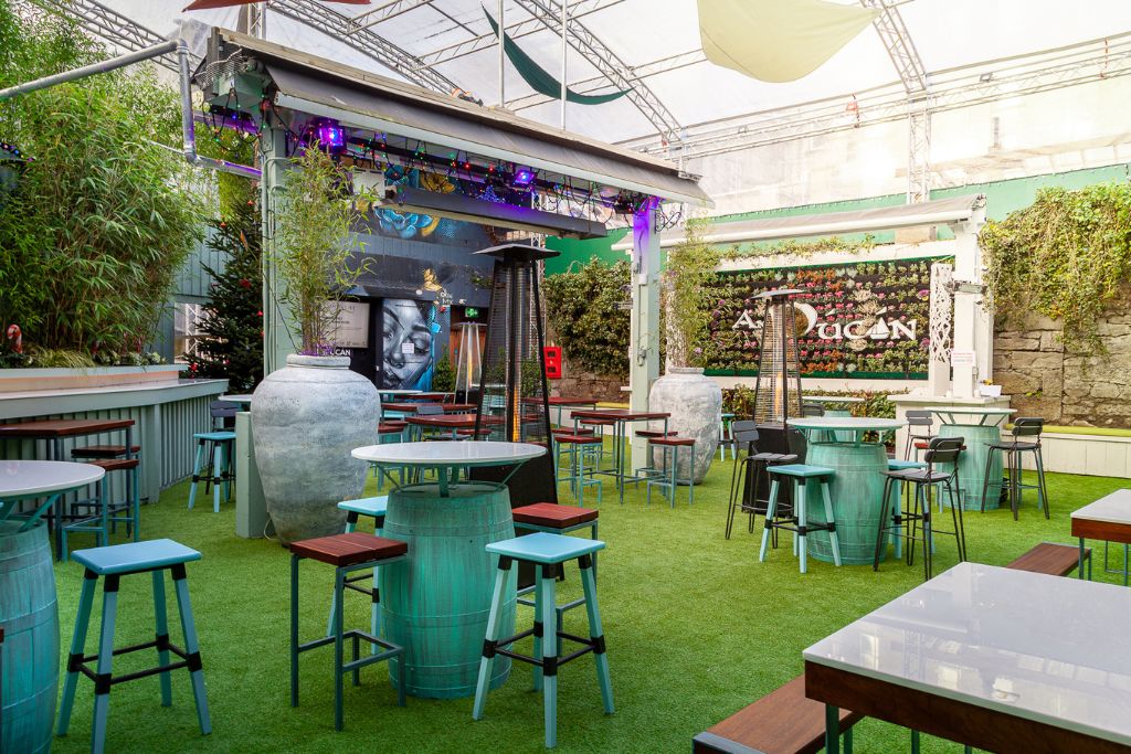 An Púcán's Vibrant Outdoor Bar and Seating Area – A trendy outdoor bar with colorful seating, a retractable roof, and a lively atmosphere, decorated with greenery and artistic elements.