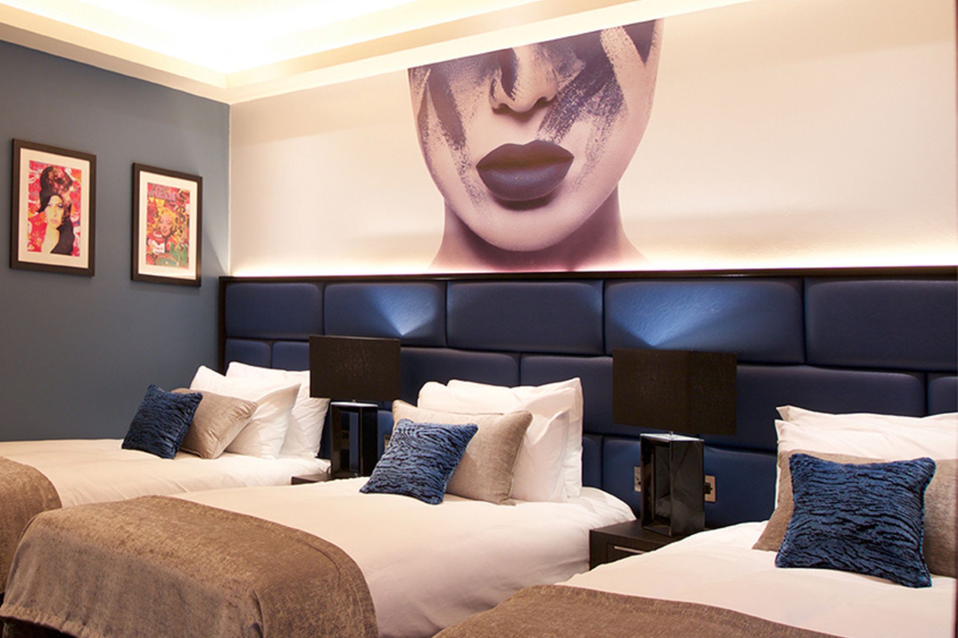 Stylish Hotel Room with Three Beds – A contemporary hotel room featuring three neatly made beds with plush headboards, artistic decor, and soft ambient lighting.