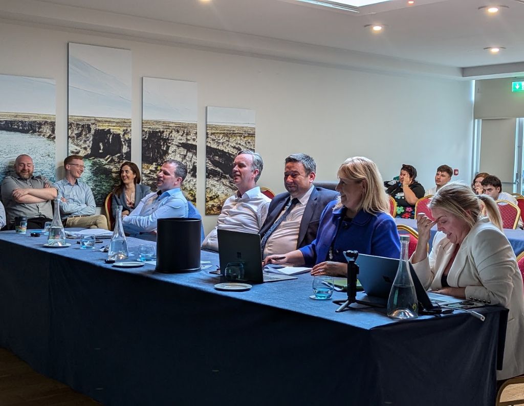 Panel of Professionals at a Conference – A group of business professionals seated at a long table, attentively listening and laughing during a hospitality or corporate event.