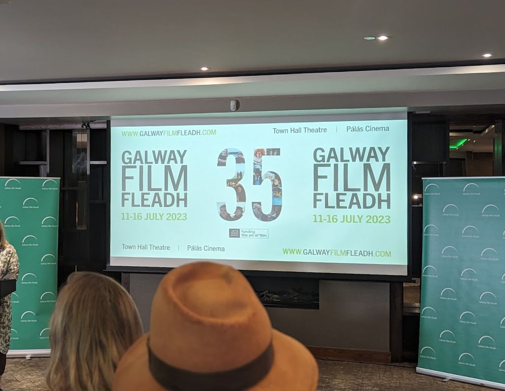 Galway Film Fleadh Presentation Screen – A projector screen displaying "Galway Film Fleadh 35" with event details for July 11-16, 2023, set inside a conference venue with attendees watching the presentation.
