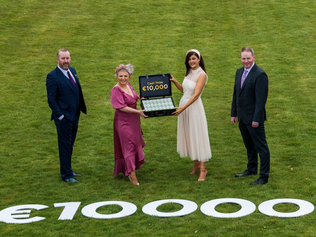 Connacht Hospitality Group & Galway Races Representatives holding briefcase with cash in front of €10,000 sign